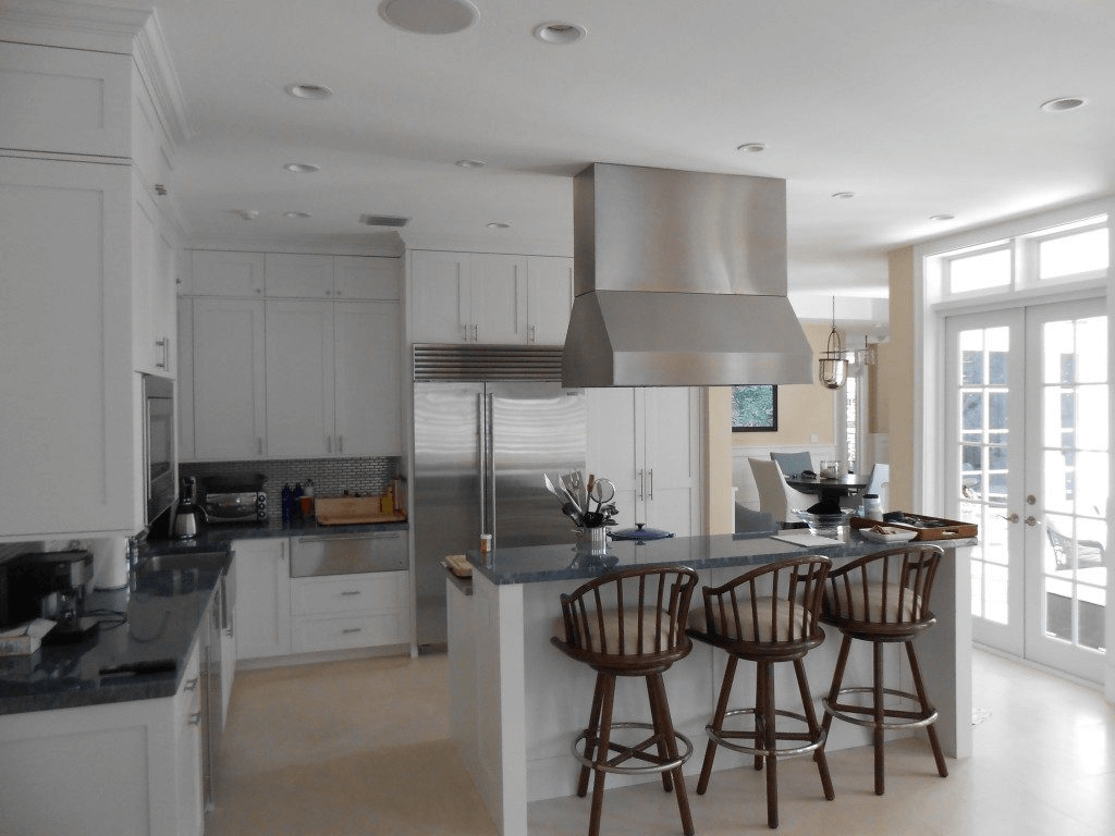 A kitchen with white cabinets and black counter tops.