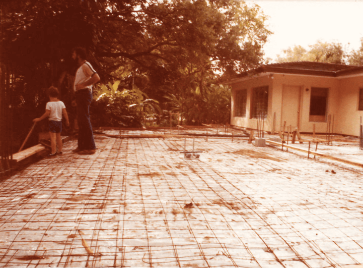 A man and child standing on the ground in front of a house.