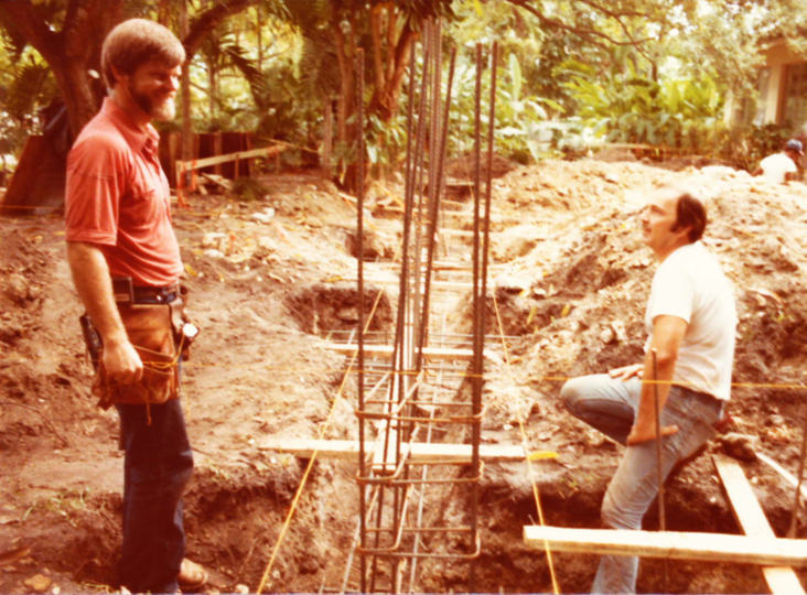 A man and woman standing on the ground near some trees.