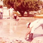 A man in white shirt and boots working on concrete.