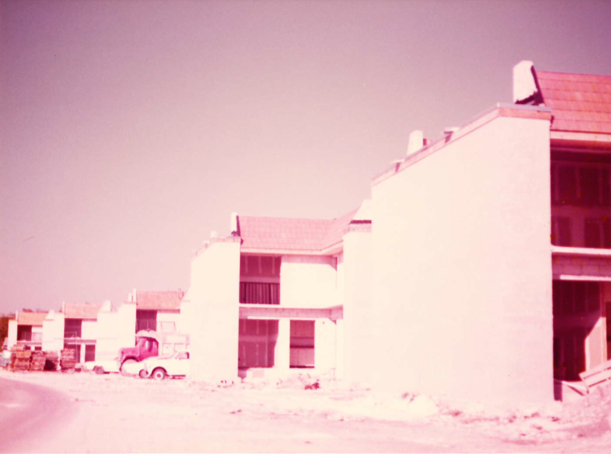 A row of houses with cars parked in front.