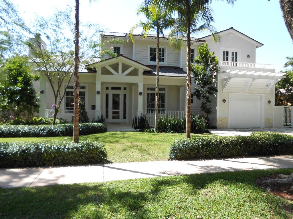 A large white house with palm trees in the front yard.